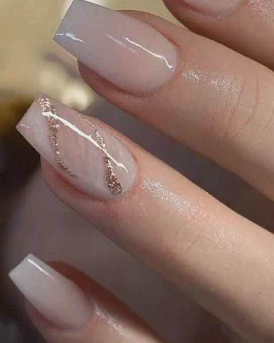 Ongles longs vernis nude avec une ligne de paillettes dorées