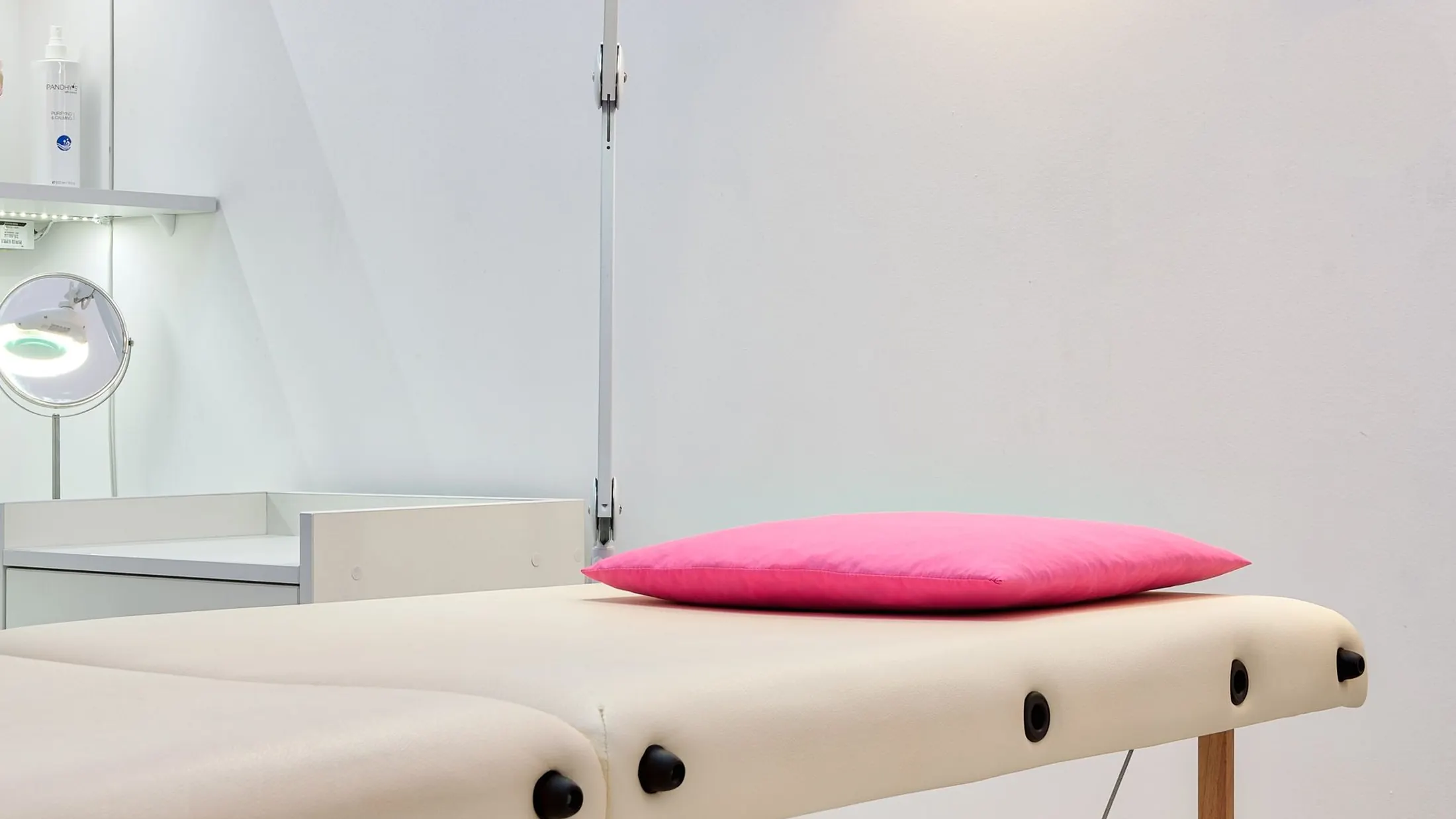 Table de soin avec un coussin rose dans une cabine claire